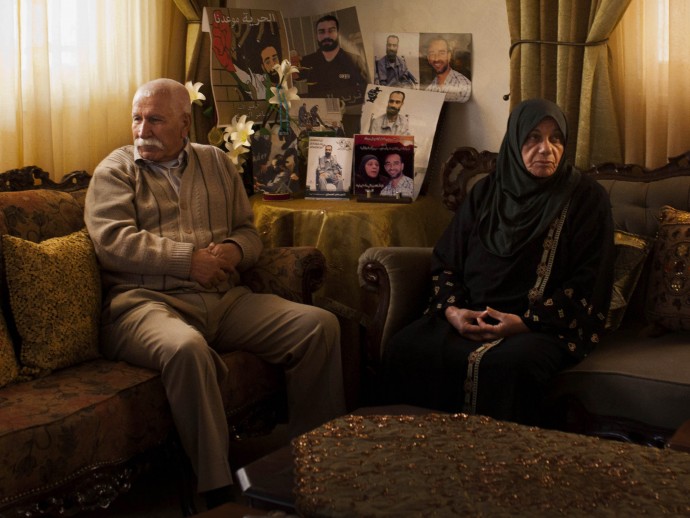 Tarek Issawi y Laila Issawi, posan para un retrato junto a las fotos de su hijo Samer Issawi en su casa en el barrio de Issawiyeh, en Jerusalén oriental, el jueves 11 de abril de 2013. El detenido Samer Issawi ha estado en huelga de hambre desde agosto cuando estaba detenido. (Foto AP / Bernat Armangue)