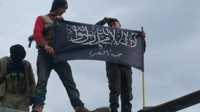 This citizen journalism image provided by Edlib News Network, ENN, which has been authenticated based on its contents and other AP reporting, shows rebels from al-Qaida affiliated Jabhat al-Nusra, wave their brigade flag as they step on the top of a Syrian air force helicopter, at Taftanaz air base that was captured by the rebels, in Idlib province, northern Syria, Friday Jan. 11, 2013. Islamic militants seeking to topple President Bashar Assad took full control of a strategic northwestern air base Friday in a significant blow to government forces, seizing helicopters, tanks and multiple rocket launchers, activists said. The Arabic words on the flag read:"There is no God only God and Mohamad his prophet, Jabhat al-Nusra (their brigade name)". (AP Photo/Edlib News Network ENN)