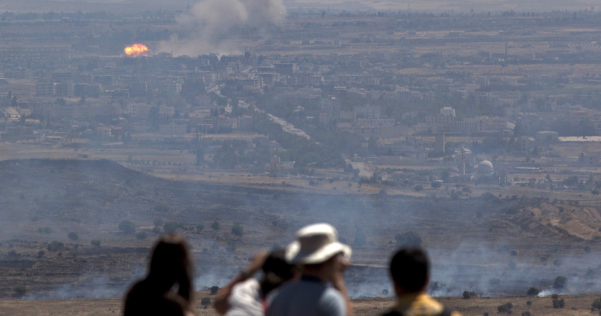 Israeli tourists look at fire caused by fighting in Syria from an observation point on Mt. Bental in the Golan Heights, near the border between Syria and Israel, Friday, June 7, 2013. (AP/Sebastian Scheiner)