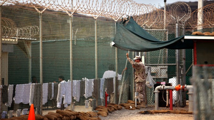 In this Jan. 21, 2009, file photo, reviewed by the U.S. Military, a guard talks to a Guantanamo detainee in the open yard in Camp 4 detention center on the U.S. Naval Base in Guantanamo Bay, Cuba. (AP/File/Brennan Linsley)