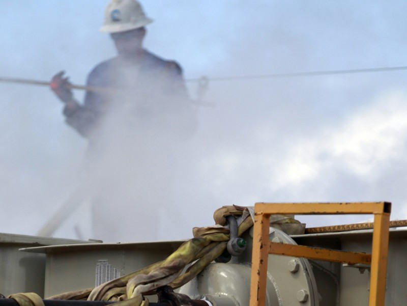 FILE - In this March 29, 2013, file photo, a worker uses a dipstick to check water levels and temperatures in a series of tanks for a hydraulic fracturing operation at an Encana Oil & Gas (USA) Inc. gas drilling site outside Rifle, Colo. (AP Photo/Brennan Linsley, File)