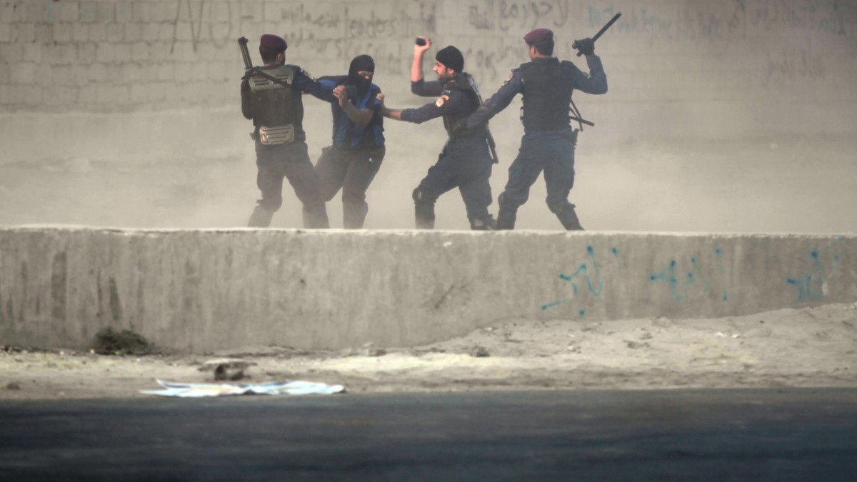 Riot police catch a Bahraini anti-government protester in the village of Shakhura, Bahrain, on Wednesday, Aug. 14, 2013. The unidentified protester ultimately slipped free of the police and escaped when other protesters came to his aid. Anti-government graffiti on the walls includes, "no dialogue with murderers." (AP/Hasan Jamali)