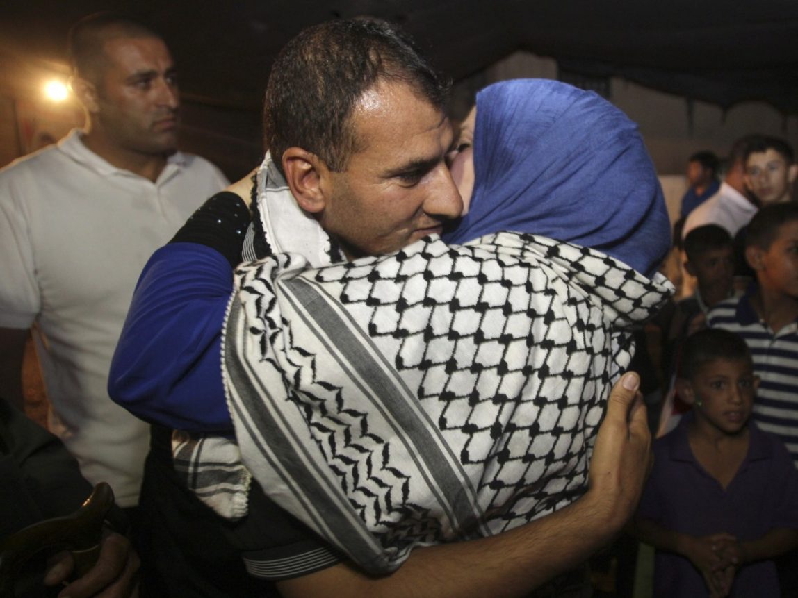 Released Palestinian prisoner Hosni Sawalha is hugged upon his arrival to his family house in Azmout village near Nablus in the West Bank, Wednesday, Aug. 14, 2013. Israel agreed to release 26 Palestinian prisoners, most of them held for deadly attacks and most have already served around 20 years, as a part of a U.S.-brokered deal that led to a resumption of Mideast negotiations. (AP Photo / Nasser Ishtayeh)