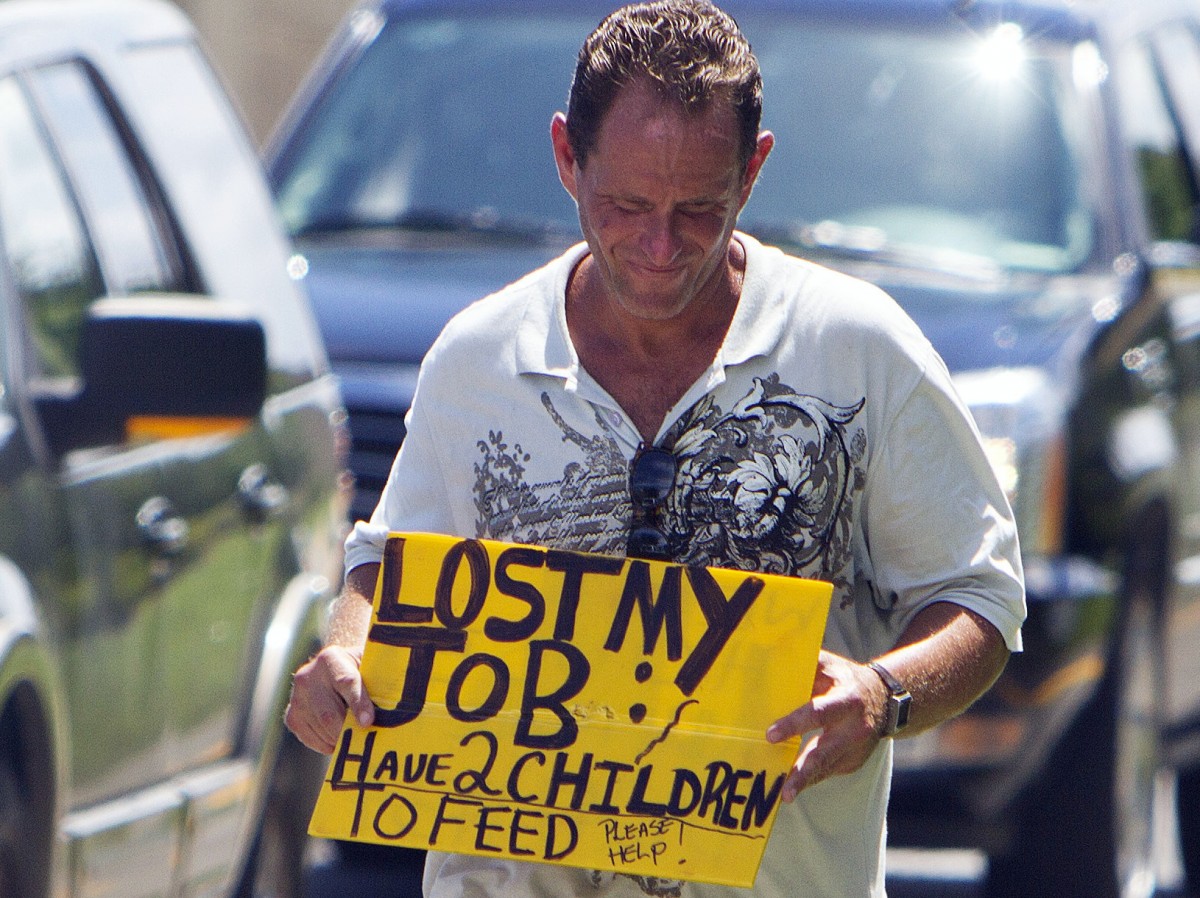FILE - A man who lost his job two months after being hurt on the job, works to collect money for his family on a Miami street corner. (AP Photo/J Pat Carter)