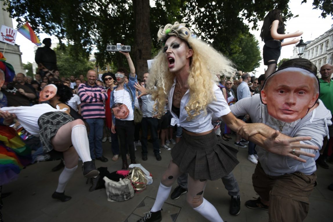 Activists stage a theatrical play where gay people are restrained by others wearing masks depicting Russian President Vladimir Putin, during a protest against Russia's new law on gays, in central London, Saturday, Aug. 10, 2013. (AP Photo/Lefteris Pitarakis))