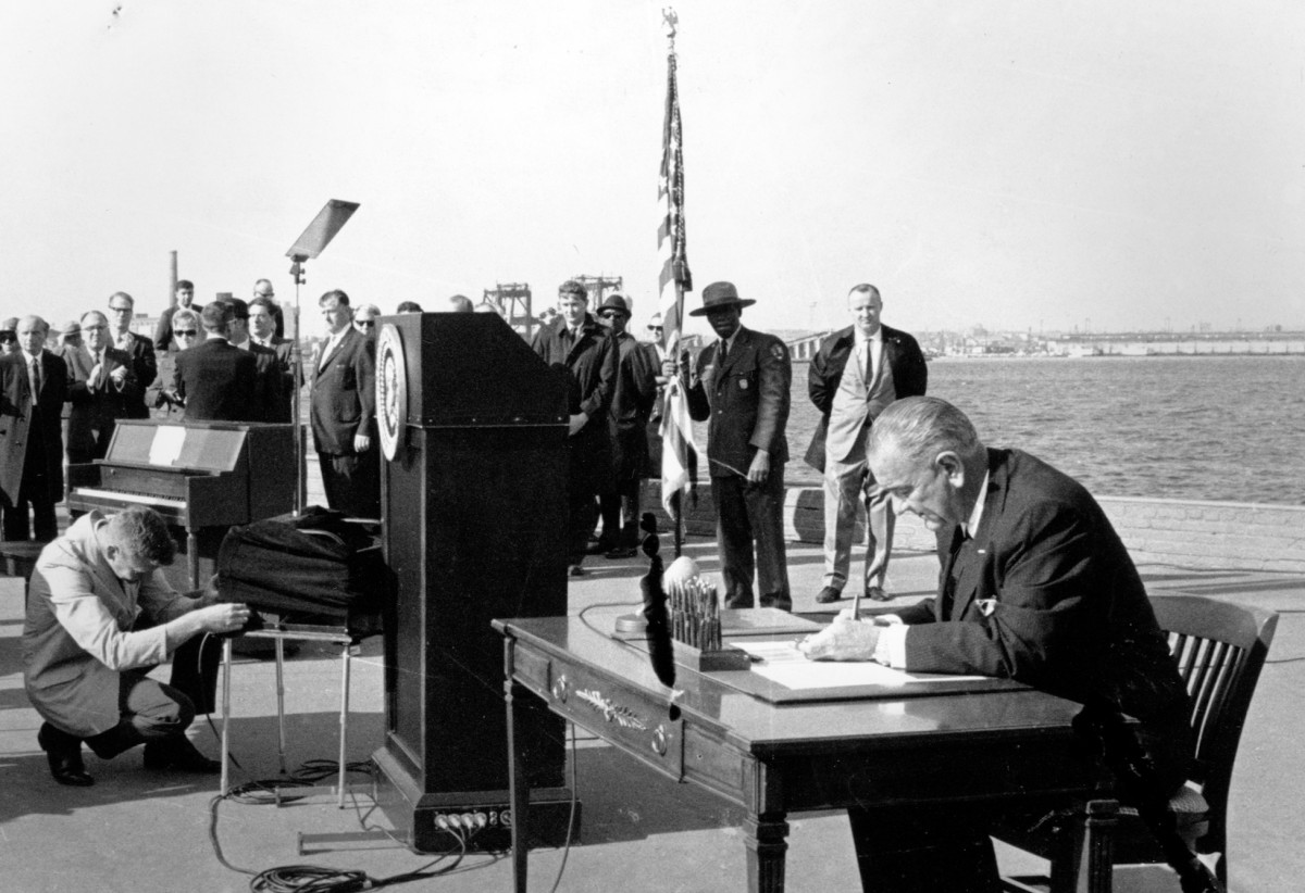 FILE - In this Oct. 3, 1965, file photo U.S. President Lyndon B. Johnson sits at his desk on Liberty Island in New York Harbor as he signs a new immigration bill. It was in 1965 that the U.S. government radically changed its immigration policy, and planted the seeds for America's current demographic explosion, a shift that historians say happened in part because of a hunger for change and equality created by the civil rights movement. (AP Photo/stf, File)