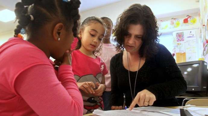 ** HOLD TO MOVE WITH STORY BY TERRY CHEA ** In this photo taken Friday, Feb. 12, 2010, teacher Lori Peck, reviews first grader Dasia Tagliaboschi's, second from left, journal during class at Grace L. Patterson Elementary school in Vallejo, Calif. Education is expected to see more cuts in funding due to California's budget crisis, the Vallejo City Unfied School District has increased class size from 20 to 28 students this year and are expected to get bigger next year.(AP Photo/Rich Pedroncelli)