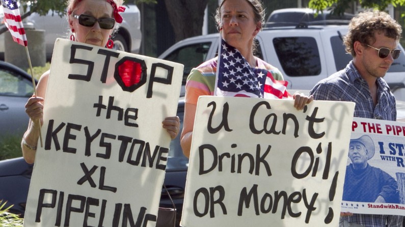 Protestors opposed to the Keystone XL pipeline hold signs outside the office of Rep. Lee Terry, R-Neb., in Omaha, Neb., Tuesday, July 26, 2011. Lawmakers in the Republican-controlled House of Representatives are slated to vote Tuesday on a bill, introduced by Terry, that would force U.S. President Barack Obama to make a decision on TransCanada's Keystone XL pipeline by Nov. 1. Environmental groups, meantime, have maligned the proposed pipeline, citing the high levels of greenhouse gas emissions associated with Alberta's oilsands. They also point to devastating oil spills like the one in rural Michigan last summer along another Canadian pipeline ó this one operated by Enbridge Inc. ó that also carried diluted bitumen, which environmentalists say is more corrosive than regular crude and poses extra risks to pipelines. (AP Photo/Nati Harnik)