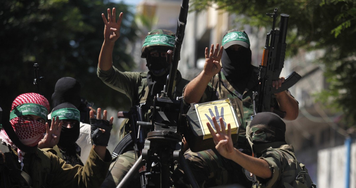 Palestinian members of the Ezz Al-Din Al Qassam militia, the military wing of Hamas, hold up four fingers, a sign that protesters say symbolizes the Rabaah al-Adawiya mosque in Cairo, Egypt, as holding their weapons during a march in Beit Lahia, northern Gaza Strip, Friday, Sept. 6, 2013. (AP/Hatem Moussa)