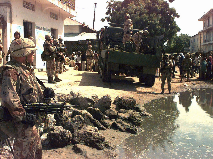 U.S. Marines load ammunition and weapons seized in a raid on Mogadishu, Somalia's, Bakara Market December 2006. A Marine stands holding a M60 machine gun, left, pointing it at a crowd of Somali civilians standing at the right. (Photo/Expert Infantry via Flickr)