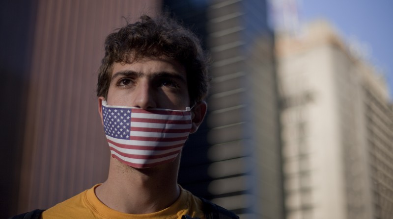 A demonstrator wearing a representation of the U.S. flag over his mouth participates in a protest outside the regional office of the presidency in Sao Paulo, Brazil, Thursday, July 18, 2013. Demonstrators gathered to show their discontent against the government's rejection of National Security Agency leaker Edward Snowden's asylum application, in early July. (AP Photo/Andre Penner)
