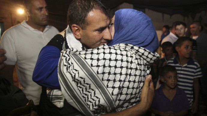 Released Palestinian prisoner Hosni Sawalha is hugged upon his arrival to his family house in Azmout village near Nablus in the West Bank, Wednesday, Aug. 14, 2013. Israel agreed to release 26 Palestinian prisoners, most of them held for deadly attacks and most have already served around 20 years, as a part of a U.S.-brokered deal that led to a resumption of Mideast negotiations. (AP Photo / Nasser Ishtayeh)