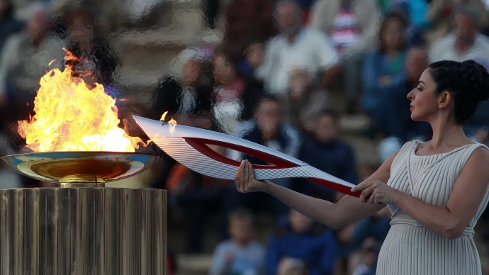 Actress Ino Menegaki, playing the role of  high priestess, lights the torch with the Olympic Flame during a handover ceremony in Athens' Panathinaiko Stadium, on Saturday, Oct. 5, 2013. The Olympic flame has been handed to organizers of the Sochi Winter Olympics in a ceremony at the site of the first modern summer games. After a seven-day run through Greece, the flame will cover 40,000 miles on Russian soil. The record-setting relay will start on Monday in Moscow and finish in Sochi on Feb. 7, the opening day of the games. (AP Photo/Kostas Tsironis)