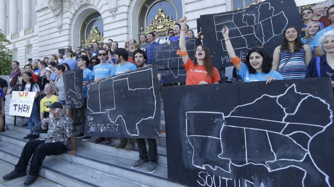 College students and supporters hold up signs at a rally to support fossil fuel divestment outside of City Hall in San Francisco, Thursday, May 2, 2013. In an effort to slow the pace of climate change, students at more than 200 colleges are asking their schools to stop investing in fossil fuel companies. (AP Photo/Jeff Chiu)