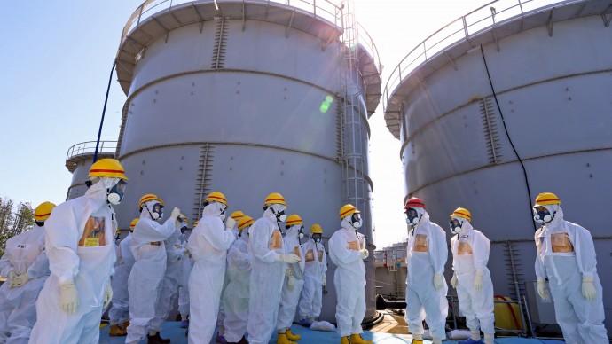 Japanese Prime Minister Shinzo Abe, third right, wearing a red helmet, is briefed about tanks containing radioactive water by Fukushima Dai-ichi nuclear power plant chief Akira Ono, fourth right, during his inspection tour to the tsunami-crippled plant in Okuma, Fukushima Prefecture, northeastern Japan, Thursday, Sept. 19, 2013. During his three-hour tour, Abe was shown some of the 1,000 tanks containing radioactive water, a water treatment equipment and a chemical dam being installed along the coast — steps meant to contain the radiation-contaminated water leakage. (AP Photo/Japan Pool)  JAPAN OUT
