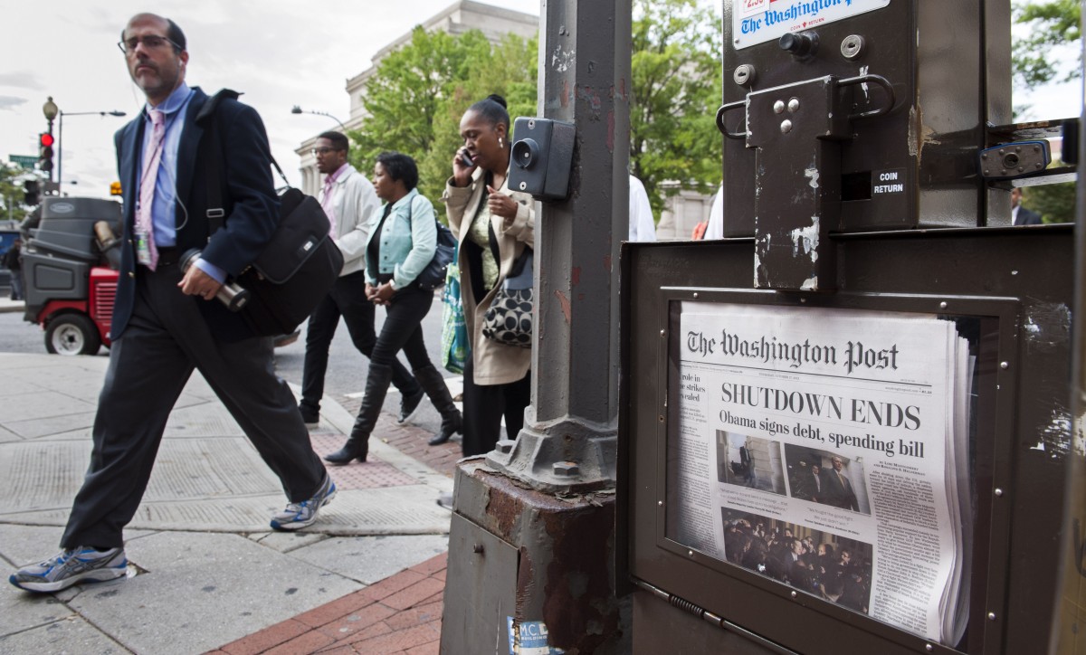 People pass a Washington Post newspaper box as they head to work near Pennsylvania Ave., NW, in Washington, Thursday, Oct. 17, 2013. (AP Photo/Cliff Owen)