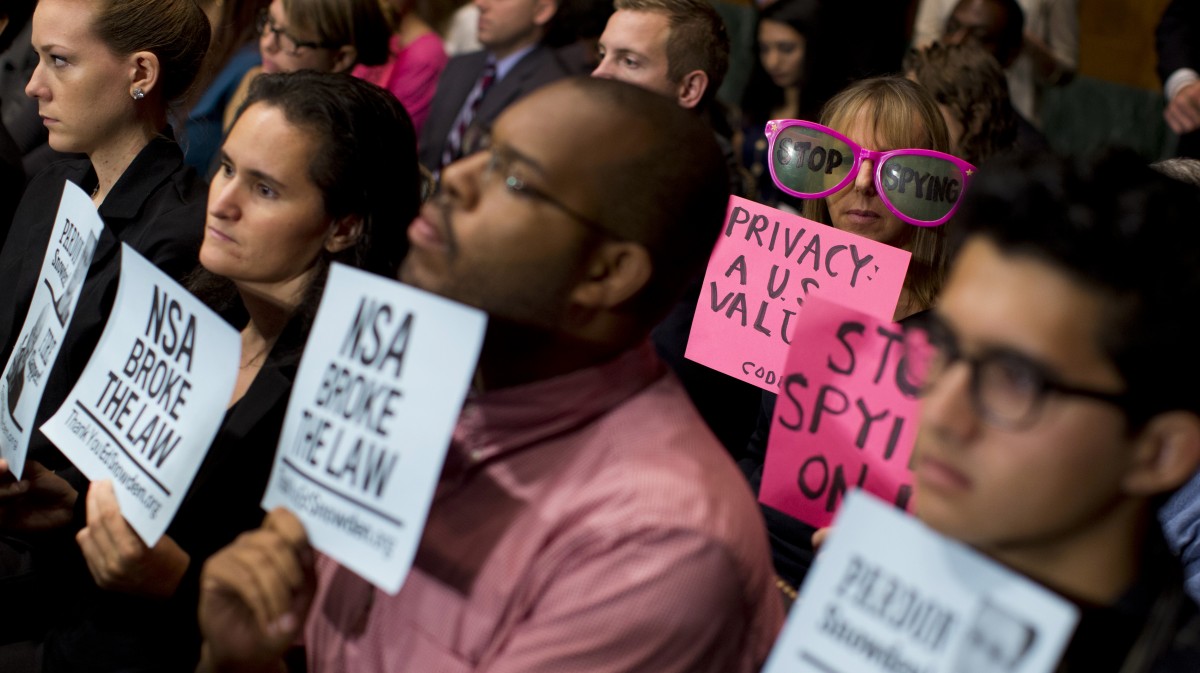 Protestors hold signs, and CodePink founder Medea Benjamin wears oversized sunglasses on Capitol Hill in Washington, Oct. 2, 2013, during a Senate Judiciary Committee oversight hearing on the Foreign Intelligence Surveillance Act with National Security Agency Director Gen. Keith Alexander and National Intelligence Director James Clapper. (AP/Evan Vucci)