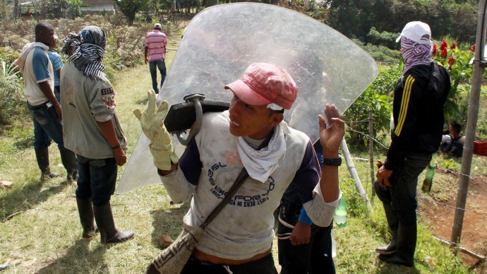 A protester carries a shield taken from riot police during clashes along the Pan American Highway in Piendamo, southern Colombia, Wednesday, Aug. 21, 2013. Farmers, truckers and health workers have joined miners and some labor unions in protests  and roadblocks for an array of demands that include reduced  gasoline prices, increased subsidies, the cancellation of free trade agreements and the end of a crackdown on illegal mining operations. (AP Photo/Juan Bautista Diaz)