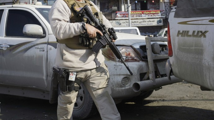 A member of security escorts a U.S. convoy in to the Kabul police headquarters, where a an American advisor was killed in Kabul, Afghanistan, Monday, Dec. 24, 2012. (AP Photo/Musadeq Sadeq)