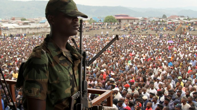 A soldier from the M23 rebel group looks on as thousands of Congolese people listen during an M23 rally, in Goma, eastern Congo, Wednesday, Nov. 21, 2012. Thousands of Congolese soldiers and policemen defected to the M23 rebels Wednesday, as rebel leaders vowed to take control of all Congo, including the capital Kinshasa. The rebels organized a rally at Goma's Stadium of Volcanoes after seizing control of the strategic city in eastern Congo Tuesday. (AP Photo/Marc Hofer)