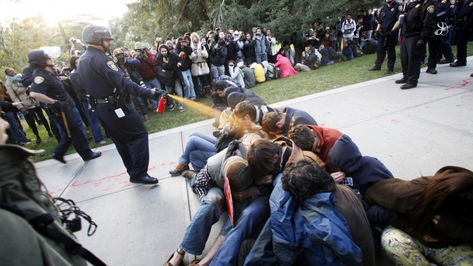 FILE - In this Nov. 18, 2011 file photo, University of California, Davis Police Lt. John Pike uses pepper spray to move Occupy UC Davis protesters while blocking their exit from the school's quad in Davis, Calif. The University of California has agreed to pay nearly $1 million to settle a lawsuit filed by demonstrators who were pepper-sprayed in the face during an Occupy protest, an incident that became a defining moment in the short-lived movement against economic inequality. (AP Photo/The Enterprise, Wayne Tilcock, File)