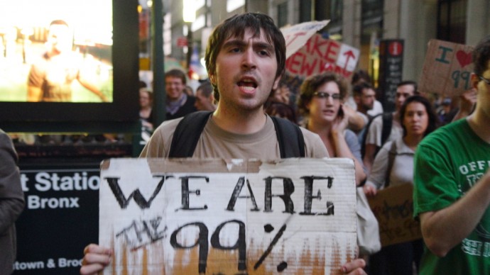 A protester holds a "We Are The 99%" sign at a September 2011 Occupy Wall Street protest in New York. The issue of unequal recovery from the 2008 financial collapse, raised at the Wall Street protests, has been further highlighted by a recent study of U.S. Census data by the Pew Center. (Photo/PaulSteinJC via Flickr)