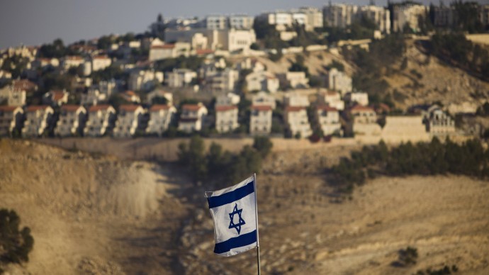 FILE - In this Monday, Sept. 7, 2009 file photo, an Israeli flag is seen in front of the West Bank Jewish settlement of Maaleh Adumim on the outskirts of Jerusalem. Israel risks losing hundreds of millions of dollars in research grants over Europe's tough new anti-settlement stance _ the heftiest price the Jewish state has ever been asked to pay for continued building on occupied lands the Palestinians want for their state. (AP Photo/Bernat Armangue, File)
