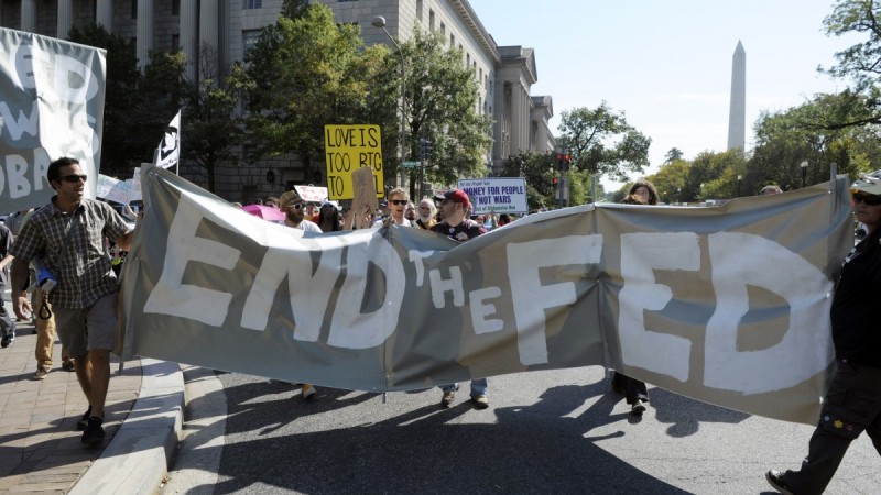 With the Washington Monument behind them, protesters cal for the end of the Federal Reserve, Sunday, Oct. 9, 2011. (AP Photo/Cliff Owen)