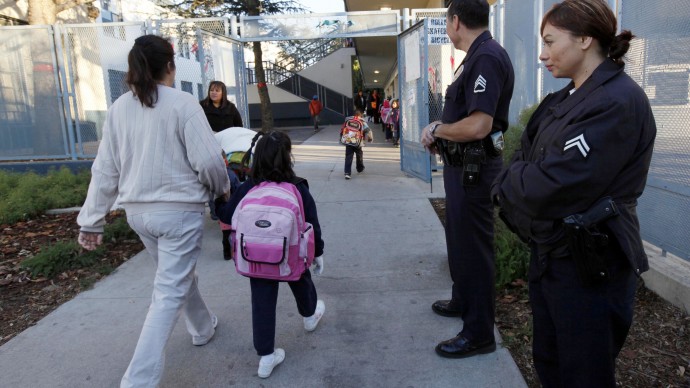 Los Angeles police officer Sgt. Frank Preciado with officer Wendy Reyes, right,  keeps watch over children arriving at the Main Street Elementary School after winter break on Monday Jan. 7,2013 in Los Angeles. Los Angeles schools reopened after winter break with tighter security in the wake of the massacre at Sandy Hook Elementary School in Connecticut. The nation's second-largest school district reopened Monday with police and county sheriff's deputies planning extra patrols at campuses. (AP Photo/Nick Ut)
