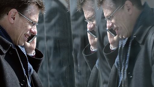 In this Tuesday, Feb. 26, 2013, file photo, a man is reflected in paneling as he speaks on his phone at the Mobile World Congress (AP Photo/Manu Fernandez, File)