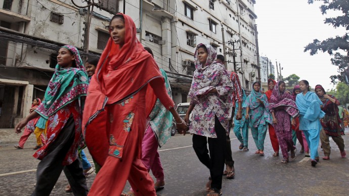 Bangladesh's garment factory workers come out from a building during their lunch time in Dhaka, Bangladesh, Saturday, June 15, 2013. Bangladeshi garment factories are routinely built without consulting engineers. Many are located in commercial or residential buildings not designed to withstand the stress of heavy manufacturing. Some add illegal extra floors atop support columns too weak to hold them, according to a survey of scores of factories by an engineering university that was shown to The Associated Press. (AP Photo/A.M. Ahad)