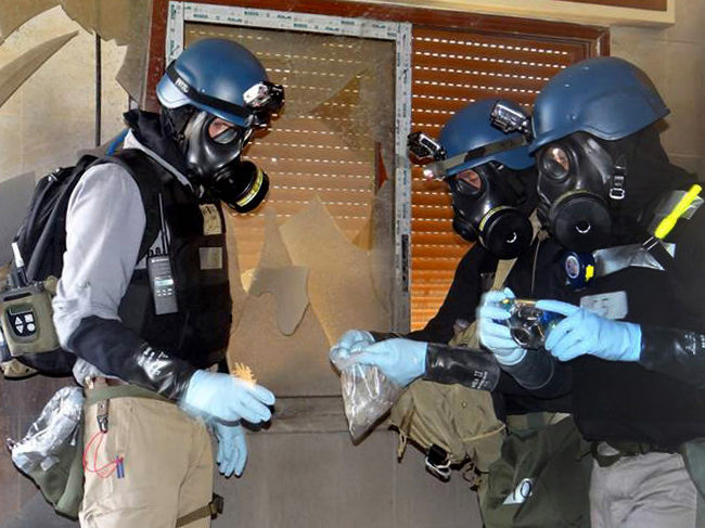 Members of the UN investigation team take samples from the ground in the Damascus countryside of Zamalka, Syria, During the dismantling of Syria's chemical weapons stockpile in 2013. (AP/Local Committee of Arbeen)