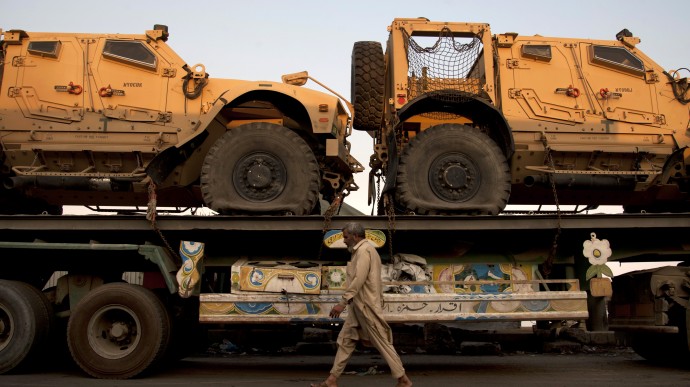 A Pakistani man walks by a truck carrying NATO military vehicles at a terminal in Karachi, Pakistan, Tuesday, Nov. 26, 2013. Trucks carrying NATO troop supplies to Afghanistan remained stuck in Pakistan on Tuesday as concern lingered about demonstrators seeking to stop the vehicles in protest of U.S. drone strikes, Pakistani transportation officials said. (AP Photo/Shakil Adil)
