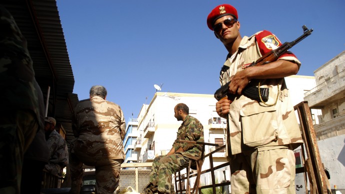 Libyan security forces stand guard as people turn in weapons in Benghazi, Libya, Saturday, Sept. 29, 2012. Hundreds of Libyans have converged on a main square in Benghazi in response to a call from the military to hand over their weapons, some driving in with armored personnel carriers, vehicles with mounted anti-aircraft guns and hundreds of rocket launchers. The call by the Libyan chiefs of staff was promoted on a private TV station earlier this month. But the call may have gained traction in the wake of the attack against the U.S. consulate in Benghazi in which the American ambassador and three staffers were killed. The attack was followed by a popular uproar against armed militias which have increasingly challenged government authorities. (AP Photo/Ibrahim Alaguri)
