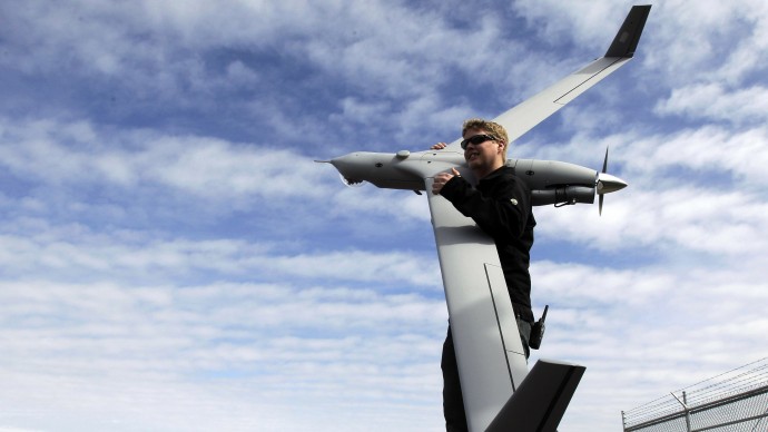 This photo taken March 26, 2013, shows flight test pilot Alex Gustafson carrying an InsituScanEagle unmanned aircraft in preparation for a flight in Arlington, Ore. It’s a good bet that in the not-so-distant future aerial drones will be part of Americans’ everyday lives, performing countless useful functions. A far cry from the killing machines whose missiles incinerate terrorists, these generally small unmanned aircraft will help farmers more precisely apply water and pesticides to crops, saving money and reducing environmental impacts. They’ll help police departments to find missing people, reconstruct traffic accidents and act as lookouts for SWAT teams. They’ll alert authorities to people stranded on rooftops by hurricanes, and monitor evacuation flows.  (AP Photo/Don Ryan)