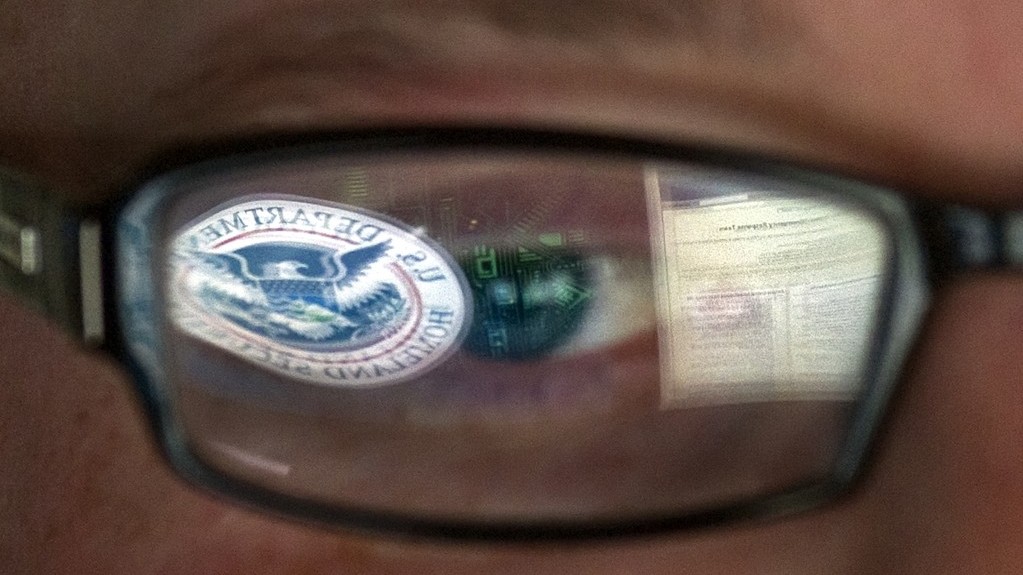 Homeland Security logo reflected in the eyeglasses of a cybersecurity analyst at the agency’s secretive cyber defense facility in Idaho.  (AP/Mark J. Terrill)