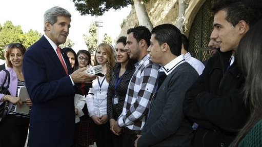 U.S. Secretary of State John Kerry greets Palestinian youth who presented him with a gift box at Manger Square in Bethlehem Wednesday, Nov. 6, 2013. Kerry was in Bethlehem to promote USAID's assistance in improving infrastructure projects in the West Bank. Kerry waded again into the nitty-gritty of faltering Israeli-Palestinian peace talks on Wednesday, saying he was optimistic that tensions and difficulties could be overcome, even as both sides traded barbs about who is to blame for the current poor state of negotiations. "As in any negotiation there will be moments of up and moments of down," Kerry told Palestinians in the West Bank town of Bethlehem after meeting Israeli Prime Minister Benjamin Netanyahu in Jerusalem and before seeing Palestinian President Mahmoud Abbas. (AP Photo/Jason Reed, Pool)