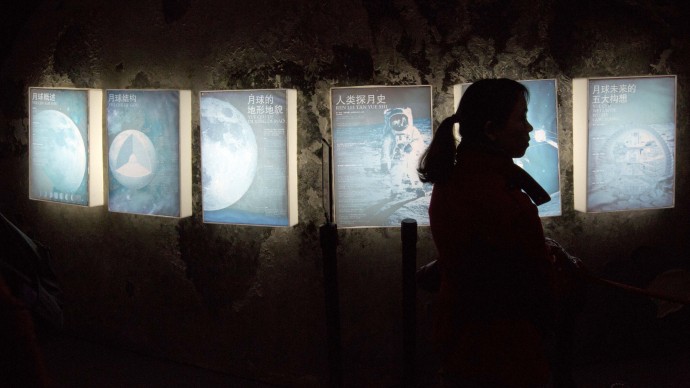 A woman is silhouetted by posters describing an exhibit on the moon at the China Science and Technology Museum in Beijing, China, Sunday, Dec. 15, 2013. China's first moon rover has touched the lunar surface and left deep traces on its loose soil, state media reported Sunday, several hours after the country successfully carried out the world's first soft landing of a space probe on the moon in nearly four decades. (AP Photo/Ng Han Guan)