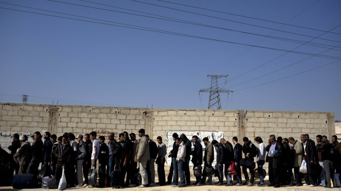 File - In this Oct. 29, 2013 file photo, men wait to be searched by the Syrian military after they have crossed from the rebel held suburb of Moadamiyeh to the government held territory in Damascus, Syria. Israel's Defense Minister Moshe Yaalon said Tuesday Dec. 3, 2013,  that Israel is transferring food, including baby food, as well as water and other “basic needs” to Syria.  (AP Photo/Dusan Vranic, File)