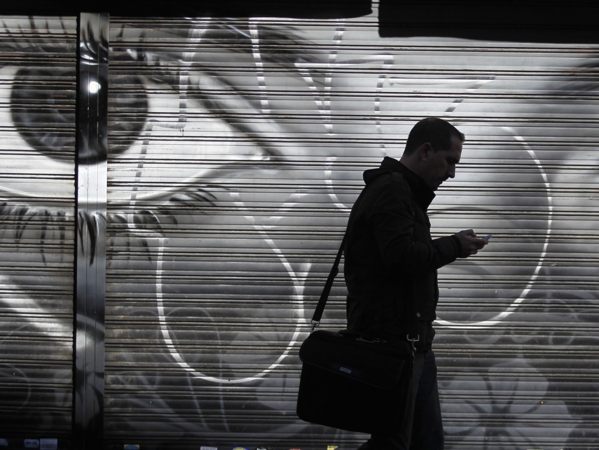 A man looks at his cell phone as he walks on the street.