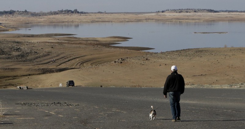 In this Jan. 9, 2014 file photo, a visitor to Folsom Lake, Calif.,  walks his dog down a boat ramp that is now several hundred yards away from the waters' edge. Gov. Jerry Brown formally proclaimed California in a drought Friday Jan. 17, 2014, saying the state is in the midst of perhaps its worst dry spell in a century and the conditions are putting residents and their property in "extreme peril."  (AP Photo/Rich Pedroncelli, File)