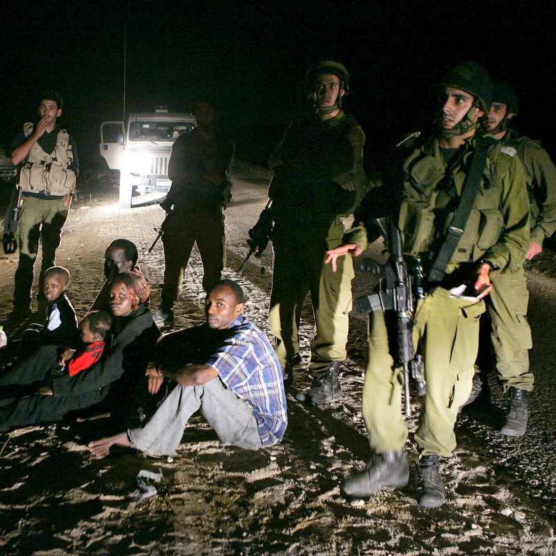 A Sudanese refugee family sit on the ground surrounded by Israeli army soldiers after they crossed illegally from Egypt into Israel. The Israeli Cabinet voted unanimously Sunday, Dec. 11, 2011, to finance a $160 million program designed to staunch the flow of illegal African migrants into Israel by stepping up construction of a border fence and expanding a detention center to hold thousands of the new arrivals. (AP Photo/Ariel Schalit, File)