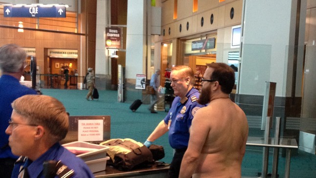 John E. Brennan stands naked after he stripped down while going through a security screening area, as a protest against airport security procedures. (AP Photo/Brian Reilly) 