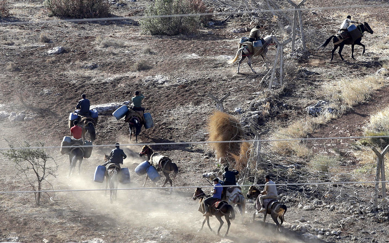 Smugglers break through the border as they enter Syrian territory near Cilvegozu, Turkey, Saturday, Sept. 7, 2013. (AP Photo/Gregorio Borgia)