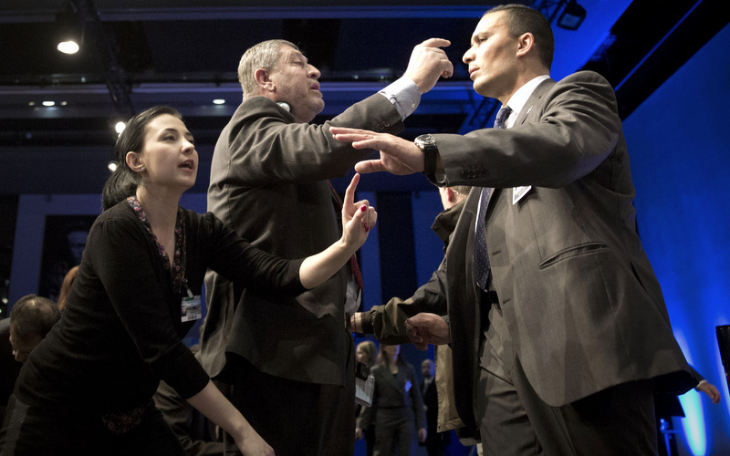 In this Wednesday, Jan. 22, 2014 picture, a UN security person tries to control journalists who jumped out of their chairs to get their questions answered. The bitterness and rancor stirred by Syria's civil war were on full display this week, both inside and outside the sealed room were seeking a way to end the conflict. (AP Photo/Anja Niedringhaus)