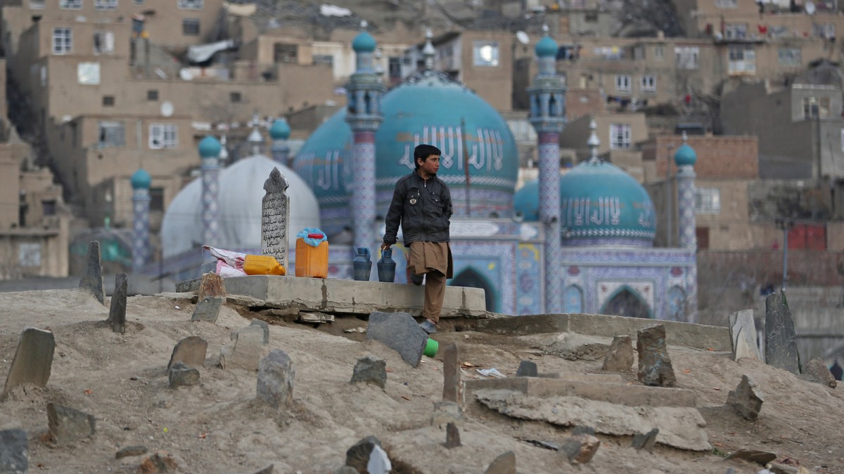 Haseeb, 13, an Afghan boy waits for customers to sell water in Kart-e Sakhi cemetery in Kabul, Afghanistan, Wednesday, Jan. 29, 2014. Children sell water in cemeteries for visitors to pour it on their relatives' graveyards. (AP Photo/Massoud Hossaini)