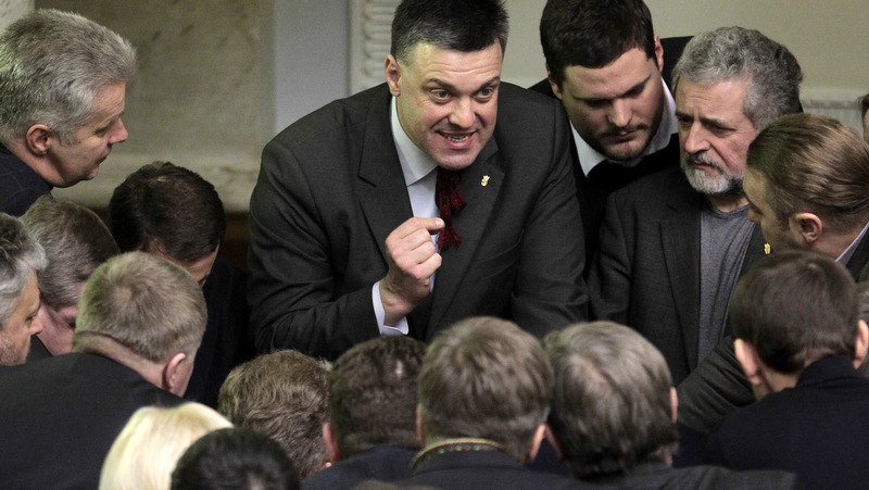 Ukrainian opposition leader Oleh Tyahnybok, center, talks to lawmakers in the parliament session hall, in Kiev, Ukraine, Tuesday, Jan. 28, 2014. In back-to-back moves to try and resolve Ukraine's political crisis, the prime minister submitted his resignation Tuesday and parliament repealed anti-protest laws that had set off violent clashes between protesters and police. (AP Photo/Sergei Chuzavkov)