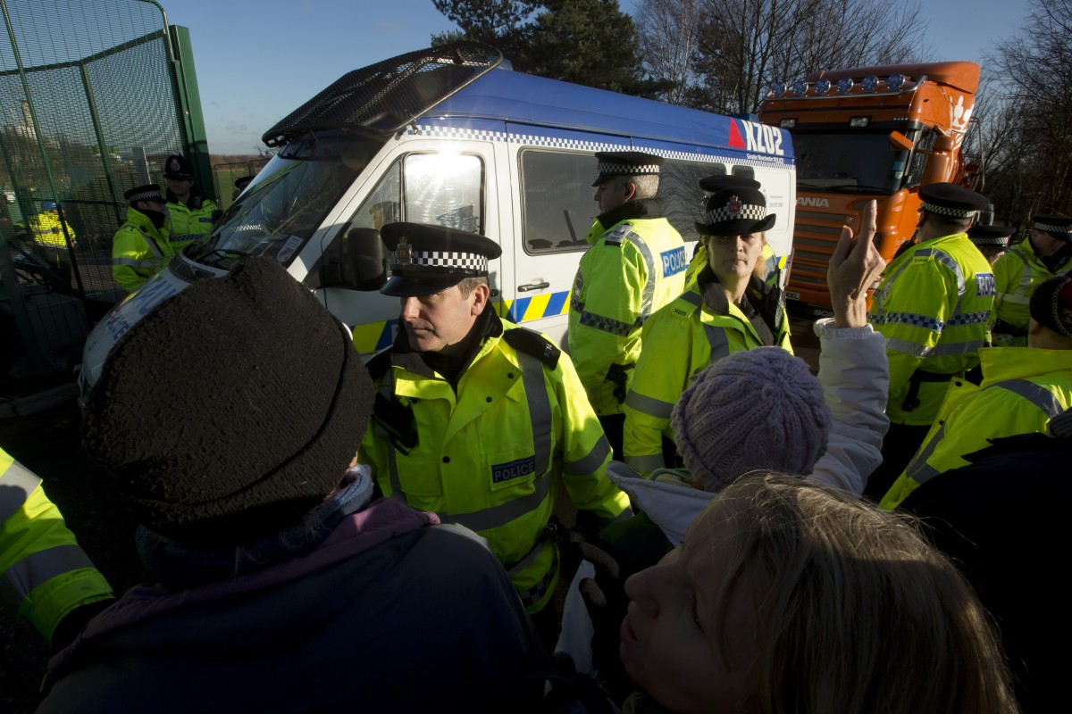 Anti-fracking protestors are moved by police as they move to stop vehicles attempting to enter an exploratory drill site for the controversial process at Barton Moss in Manchester, England, Monday, Jan. 13, 2014. Councils that back "fracking" will get to keep more money in tax revenue as part of an "all-out" drive to promote drilling, Britain's Prime Minister David Cameron has said. (AP Photo/Jon Super)