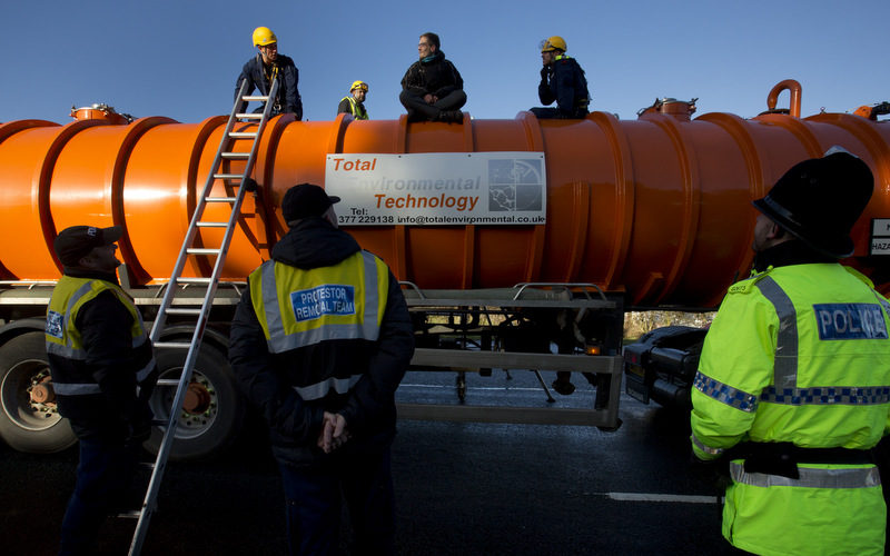 Police prepare to remove a protestor from the top of a vehicle waiting to enter an exploratory drill site for the controversial gas extraction process known as fracking at Barton Moss in Manchester, England, Monday, Jan. 13, 2014. (AP Photo/Jon Super)