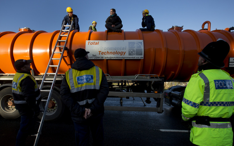 Police prepare to remove a protestor from the top of a vehicle waiting to enter an exploratory drill site for the controversial gas extraction process known as fracking at Barton Moss in Manchester, England, Monday, Jan. 13, 2014. (AP Photo/Jon Super)